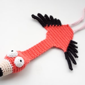 Peut inclure: Un marque-page en crochet en forme de flamant rose avec du fil rose, noir et blanc. Le marque-page a de grands yeux blancs avec des pupilles noires et un bec noir.