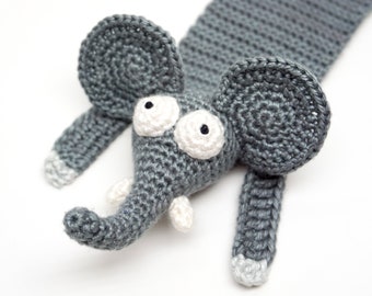 May include: A handmade gray crochet elephant with large white eyes and ears. The elephant has a trunk, two small tusks, and a long body. The tips of the ears and feet are light gray. This whimsical toy is perfect for children.