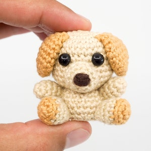 May include: A small crocheted dog toy with brown eyes, a brown nose, and tan ears and paws.