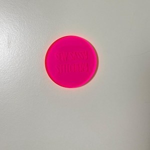 May include: A bright pink round sticker with the text "WASSY STICKERS" in white.