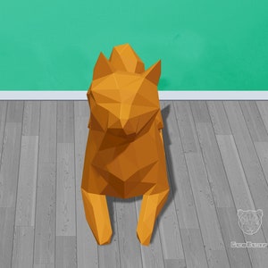 May include: A 3D origami paper model of a fox sitting on a wood floor. The fox is made of orange paper and has a triangular shape.