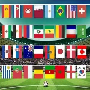 Op de afbeelding: Een verzameling van tweeëndertig rechthoekige nationale vlaggen gerangschikt in vier horizontale rijen boven een voetbalveld. Een enkele zwart-witte voetbal ligt op het groene gras op de voorgrond, onder de rijen met kleurrijke vlaggen.