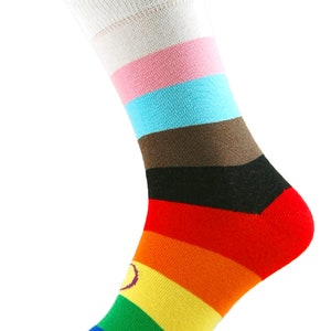 Op de afbeelding: Een paar kleurrijke gestreepte sokken met een regenboogontwerp en een paarse cirkel op de voet. De sokken hebben witte, roze, blauwe, bruine, zwarte, rode, oranje, gele, groene, blauwe en paarse strepen.