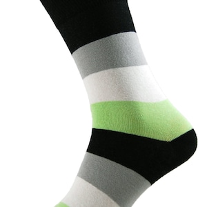 Peut inclure: Une paire de chaussettes rayées avec des rayures noires, grises, blanches et vertes. Les chaussettes sont pliées et affichées sur un fond blanc.