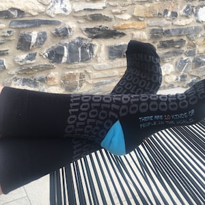 May include: Black socks with a blue heel and a pattern of 1s and 0s. The socks have the text "There are 10 kinds of people in the world." printed on them.