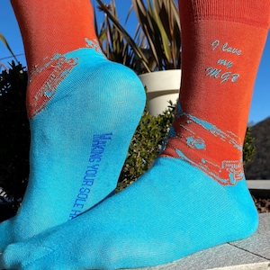 Puede incluir: Un par de calcetines naranja y azul con un gráfico de un coche y el texto "I love my MGB" en un calcetín. Los calcetines están hechos por "Funky You Sole"
