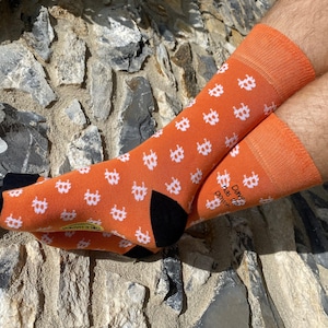 May include: Orange socks with a white Bitcoin symbol pattern. The socks have black heels and toes. One sock has the text "Dave has the power" on the side.