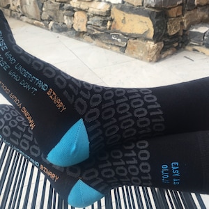 Könnte beinhalten: Schwarze Socken mit einem blauen und orangenen Design mit dem Text "Those who understand binary and those who don't. Making your sole easy as 011011."