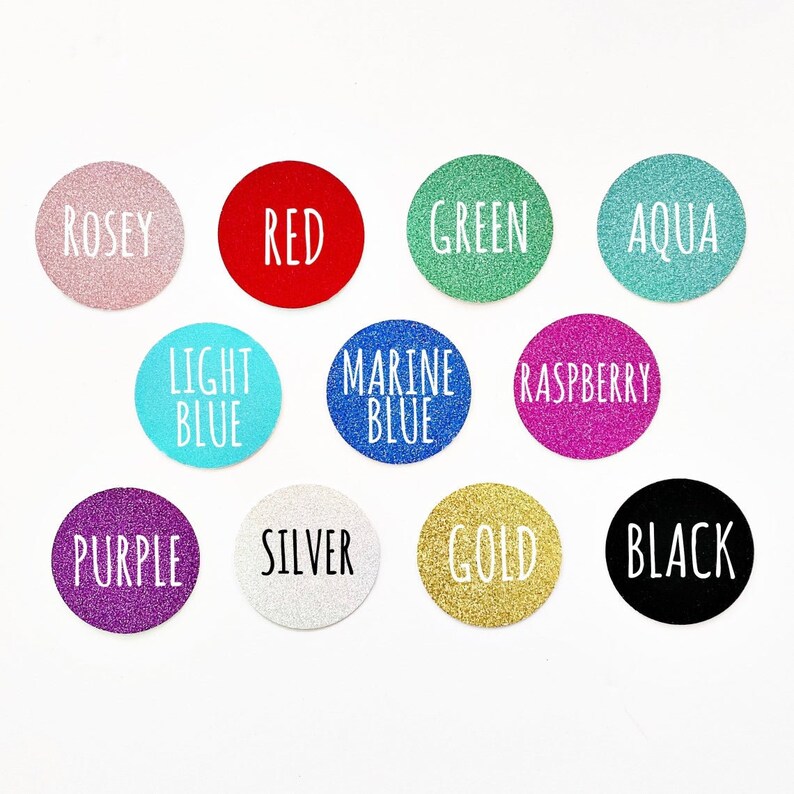 May include: Twelve round, glitter-covered stickers with various colors and text labels. The colors include rose, red, green, aqua, light blue, marine blue, raspberry, purple, silver, gold, and black. The text labels include "Rosey", "Red", "Green", "Aqua", "Light Blue", "Marine Blue", "Raspberry", "Purple", "Silver", "Gold", and "Black".