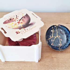 Zerbrochenes und repariertes Kintsugi auf einer in Japan hergestellten Keramikschale. Handgemalte Blumen.