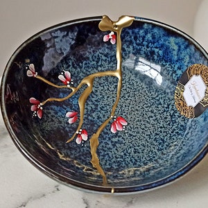 Broken and repaired Kintsugi on ceramic bowl made in Japan. Hand painted flowers.