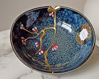 Broken and repaired Kintsugi on ceramic bowl made in Japan. Hand painted flowers.