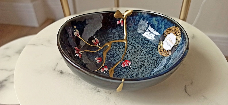 Kintsugi roto y reparado sobre cuenco de cerámica hecha en Japón. Flores pintadas a mano. imagen 2