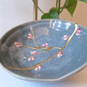 Broken and repaired Kintsugi on ceramic bowl made in Japan. Hand painted flowers.