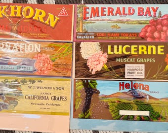 May include: Vintage fruit crate labels with colorful designs and text. The labels feature names like "Elkhorn", "Emerald Bay", "Carnation", "Lucerne", and "Helena". The labels are printed on paper and have a worn, vintage look.