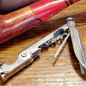 May include: A silver multi-tool with a bottle opener, corkscrew, and a small screwdriver. The tool is folded closed and has a small loop on the end.
