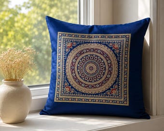 May include: A square throw pillow in deep blue featuring a centered, intricate mandala pattern embroidered in gold, red, and white threads. The design consists of concentric circles and floral motifs enclosed within a square border.