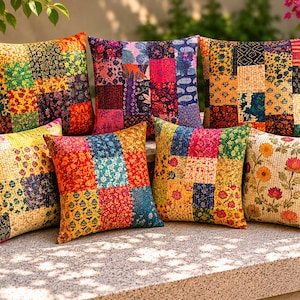 Puede incluir: Una colección de cojines decorativos de patchwork coloridos. Cada cojín presenta una combinación única de patrones florales y geométricos en tonos rojos, amarillos, azules y naranjas. Los cojines están colocados sobre una superficie de piedra.