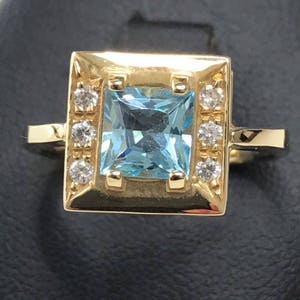Anillo en oro amarillo de 18K con swarovski y topacio azul.