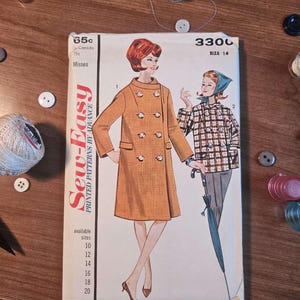 May include: Vintage sewing pattern featuring a double-breasted coat design. The pattern cover displays illustrations of the coat and a plaid jacket, with the text "Sew-Easy" and size options. The background includes sewing notions.