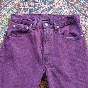 May include: A pair of purple denim jeans with a straight leg fit. The jeans have a subtle herringbone pattern and are made of a soft, comfortable fabric.