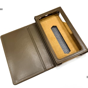 Puede incluir: Funda de cuero marr&oacute;n para un dispositivo DX340, abierta para revelar el interior. La funda tiene una abertura rectangular para la pantalla y una secci&oacute;n cubierta de malla. El logotipo de iBasso es visible en la parte superior izquierda, y "DX 340" en la parte inferior derecha.