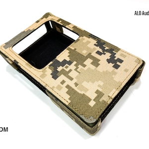 May include: A camouflage-patterned case for a portable audio player. The case is made of a durable fabric and has a cutout for the player's screen. The text "ALO Audio" is printed on the case.
