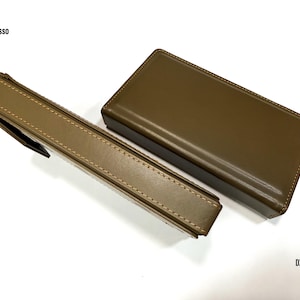 Puede incluir: Dos estuches de cuero verde oliva, uno rectangular y otro con forma de bol&iacute;grafo, se muestran sobre una superficie blanca. El estuche para bol&iacute;grafos tiene un cierre de solapa. Los textos "iBasso" y "DX 340" son visibles.