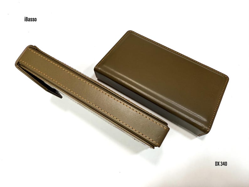 Puede incluir: Dos estuches de cuero verde oliva, uno rectangular y otro con forma de bol&iacute;grafo, se muestran sobre una superficie blanca. El estuche para bol&iacute;grafos tiene un cierre de solapa. Los textos "iBasso" y "DX 340" son visibles.