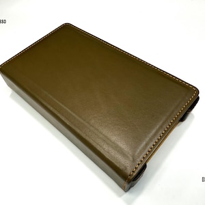 Puede incluir: Funda de cuero verde oliva con bordes cosidos. La funda tiene forma rectangular y est&aacute; etiquetada como "iBasso" y "DX 340". Parece estar dise&ntilde;ada para guardar un peque&ntilde;o dispositivo electr&oacute;nico.