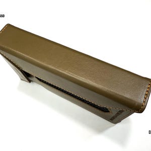 Puede incluir: Funda de cuero verde oliva para un reproductor de audio digital iBasso DX340. La funda es rectangular con un borde cosido y un panel de malla. El texto iBasso y DX 340 es visible en la funda.
