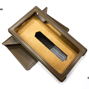 Puede incluir: Una funda de cuero marr&oacute;n para un dispositivo DX 340. La funda tiene una abertura rectangular con una inserci&oacute;n de malla negra y un interior beige. La funda est&aacute; abierta, revelando el interior, y el logotipo de iBasso es visible.