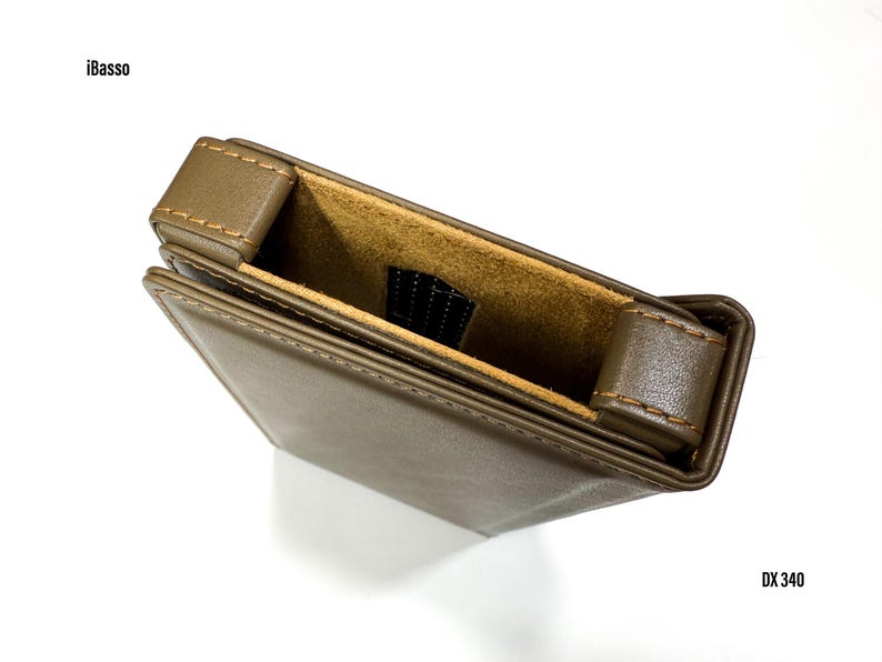Puede incluir: Una funda de cuero marr&oacute;n con interior beige. La funda rectangular tiene una solapa y est&aacute; cosida con hilo beige. Los textos "iBasso" y "DX 340" son visibles.
