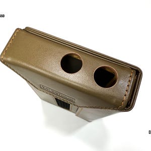 Puede incluir: Funda de cuero verde oliva con dos aberturas circulares. La funda tiene forma rectangular con un borde cosido y un acento negro. El texto "VALENTINUM" es visible en la parte delantera. Tambi&eacute;n son visibles los textos "iBasso" y "DX 340".