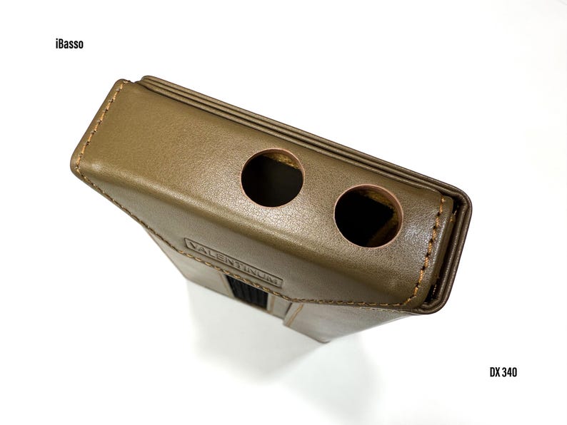 Puede incluir: Funda de cuero verde oliva con dos aberturas circulares. La funda tiene forma rectangular con un borde cosido y un acento negro. El texto "VALENTINUM" es visible en la parte delantera. Tambi&eacute;n son visibles los textos "iBasso" y "DX 340".
