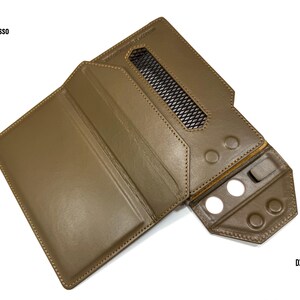 Puede incluir: Una funda de cuero marr&oacute;n para reproductor de audio digital, con el texto "iBasso" y "DX 340". La funda tiene una rejilla de ventilaci&oacute;n y varios recortes circulares para botones. La funda est&aacute; abierta, revelando el interior.