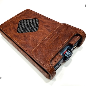 May include: A brown textured leather protective case for an iFi Audio iDSD GR 2 device. The case features a diamond-shaped cutout with a black mesh insert, visible stitching along the edges, and an open end exposing the device's black volume knob.