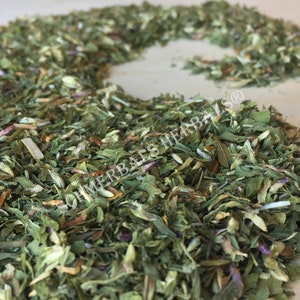 May include: A close-up of a pile of dried herbs, including green leaves, white flowers, and purple petals. The herbs are arranged in a loose, flowing pattern, creating a natural and organic aesthetic.