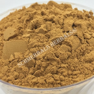 May include: A close-up of a brown powder in a clear glass bowl. The powder is labeled "SCHMERBALS HERBALS".