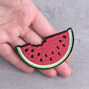 May include: A red watermelon slice with a bite taken out of it. The watermelon is embroidered with black seeds and a green rind. The patch is iron-on and can be used to decorate clothing, bags, or other items.