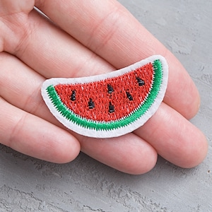 May include: A red and green embroidered watermelon patch. The watermelon is white with a green outline and red inside. The watermelon has black seeds.
