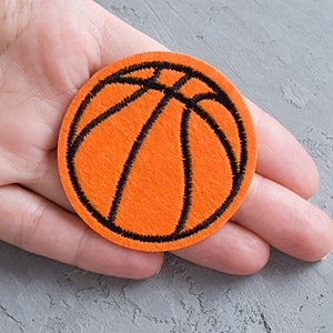 Könnte beinhalten: Orangener Filz-Basketball-Patch mit schwarzen Nähten. Der Patch hat einen Durchmesser von etwa 5 cm.