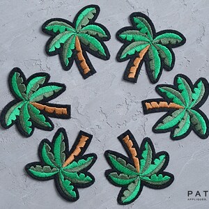 May include: Six green and brown embroidered palm tree patches on a gray background. The patches are arranged in a circle.