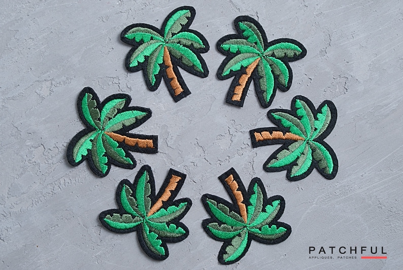 May include: Six green and brown embroidered palm tree patches on a gray background. The patches are arranged in a circle.