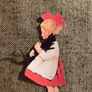 Fille de style vintage des années 1900 en robe orange pouvant contenir un chat noir, décoration d'Halloween en papier cartonné découpé à la main pour l'encadrement, décoration de cupcakes