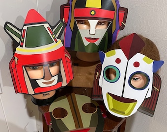 May include: Four colorful paper masks with different designs. The masks are on a wooden stand. The masks are all different colors and have different features.