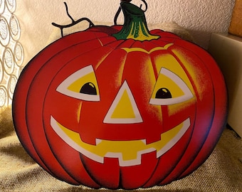 May include: A red and yellow paper jack-o'-lantern with a carved face. The pumpkin has a black stem and is decorated with black lines.