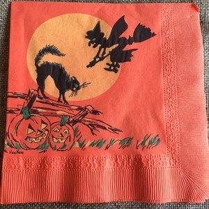 May include: Orange paper napkin with a Halloween theme. The napkin features a black cat, a witch flying on a broomstick, and two jack-o'-lanterns. The background is a large orange moon with a yellow center. The napkin is decorated with a scalloped border.