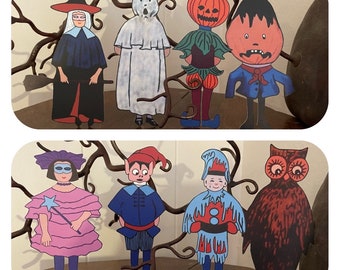 May include: A set of nine Halloween-themed paper cutouts, including a witch, a ghost, a pumpkin, a monster, a girl with a mask, a jester, an elf, a jester, and an owl. The cutouts are colorful and have a vintage style.