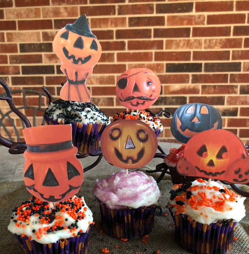 May include: Six Halloween cupcakes decorated with orange and black sprinkles. Each cupcake has a different vintage-style pumpkin face topper.